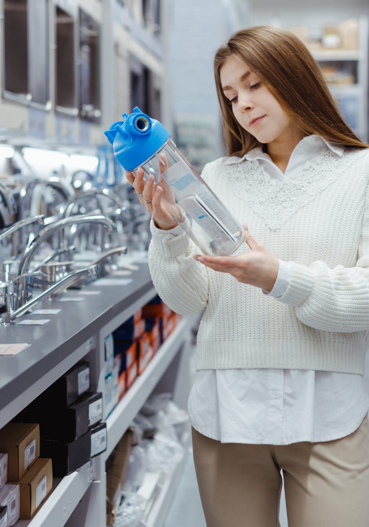 Woman holds household water filter for purification from mechanical impurities in hardware store. Repair of the water supply system at home, purchase of a filter. Woman in plumbing section
